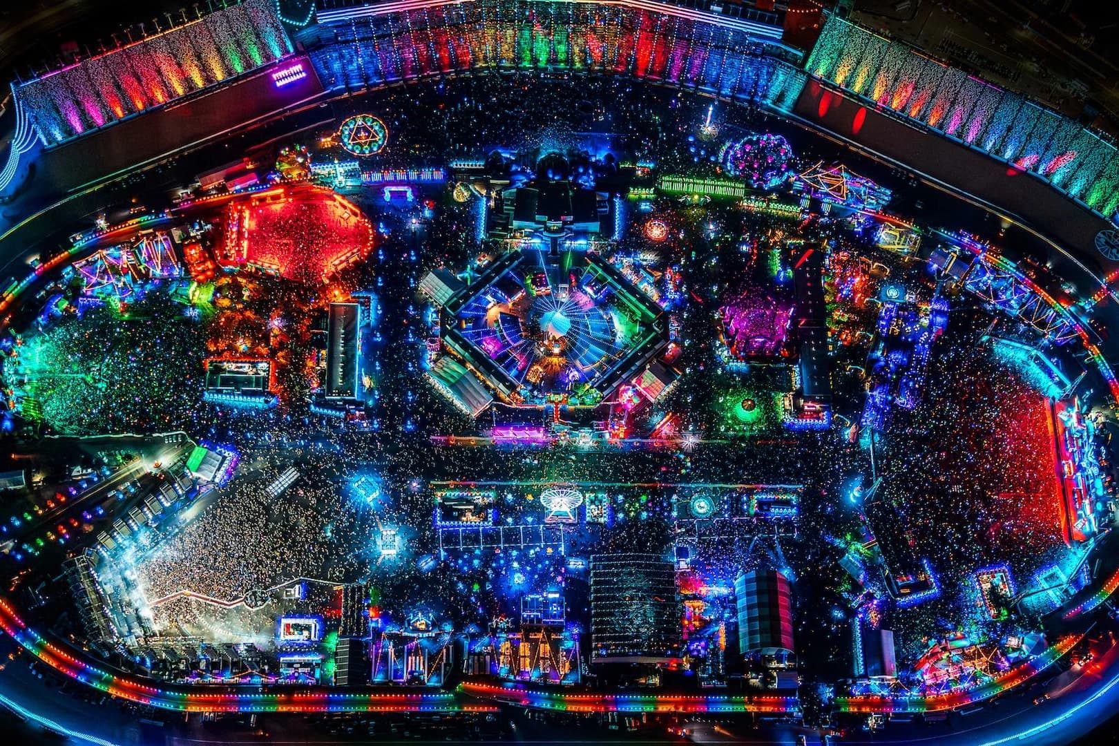 Nocne zdjęcie z lotu ptaka: owal toru Las Vegas Motor Speedway obwiedziony kolorowymi światłami, a w środku tłum oraz rozświetlone sceny i instalacje EDC Las Vegas z ośmiokątną sceną pośrodku, fot. Jamal Eid dla EDC Las Vegas